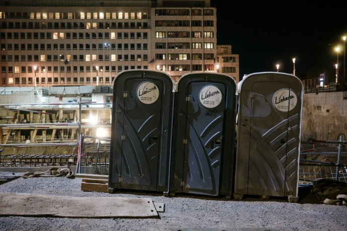 Three portable toilets at a construction site at night